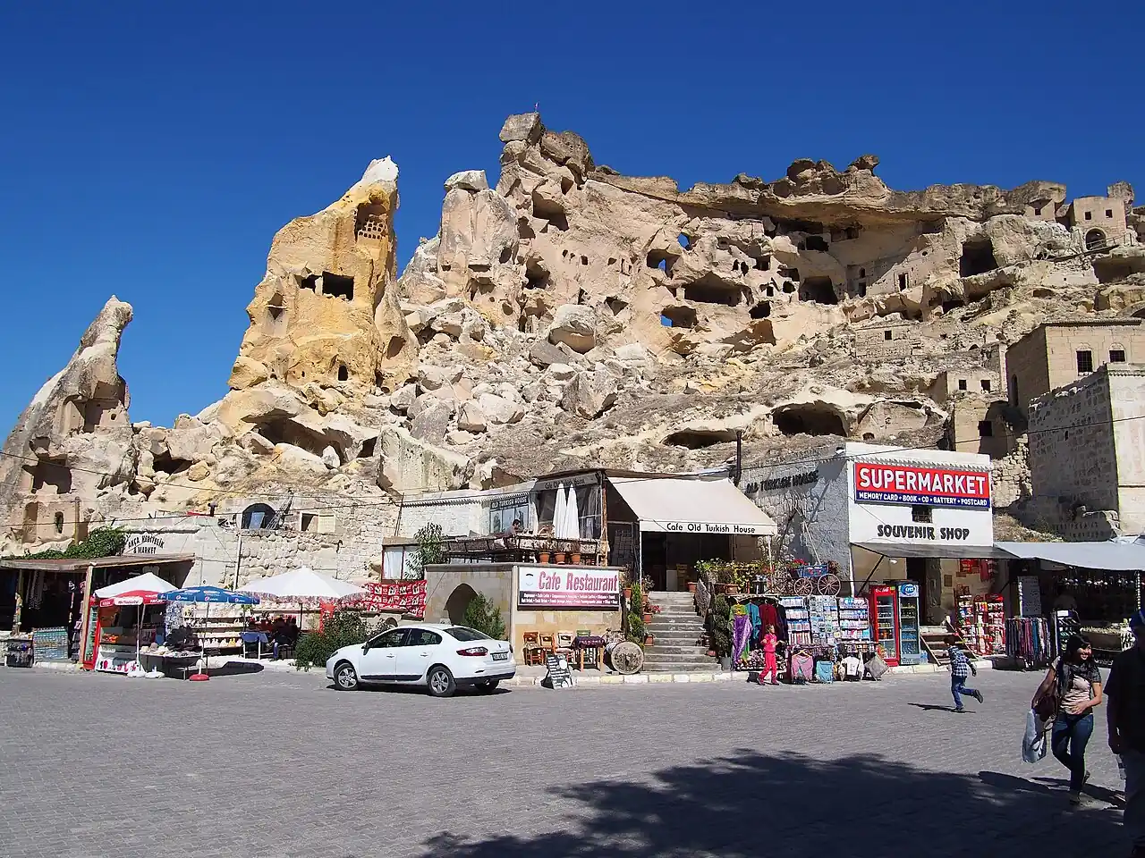 Historic rock-cut cave dwellings above shops at Çavuşin village in Cappadocia.